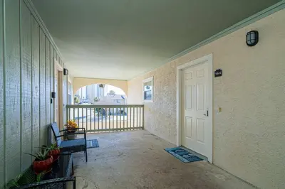 an empty hallway with a white door and a balcony at The Turtle Nest - Resort Condo with Pool in Panama City Beach
