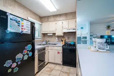 a kitchen with a black refrigerator and a sink at The Turtle Nest - Resort Condo with Pool in Panama City Beach