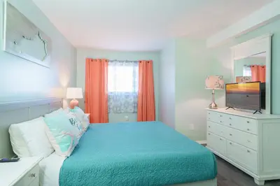 a bedroom with a bed and a dresser with a television at Turtle Love - Resort Amenities & Ocean Views in Panama City Beach