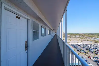 a balcony with a white door and a parking lot at Turtle Love - Resort Amenities & Ocean Views in Panama City Beach