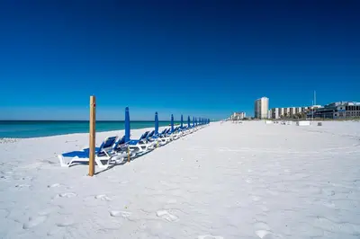 a row of beach chairs on a sandy beach at Turtle Love - Resort Amenities & Ocean Views in Panama City Beach