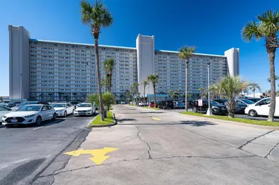 a parking lot with cars parked in front of a large building at Turtle Love - Resort Amenities & Ocean Views in Panama City Beach
