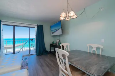 a dining room and living room with a table and chairs at Turtle Love - Resort Amenities & Ocean Views in Panama City Beach