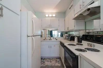 a kitchen with white cabinets and a white refrigerator at Turtle Love - Resort Amenities & Ocean Views in Panama City Beach