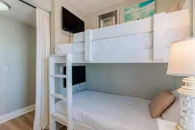 a bedroom with two bunk beds with a television at Whitesands Retreat - Incredible Resort Home in Panama City Beach