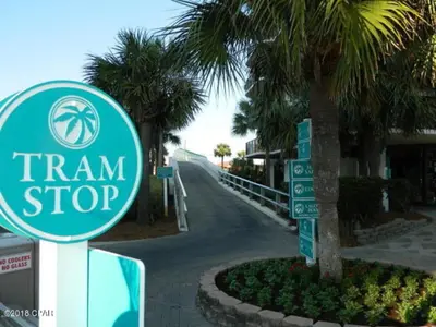 a sign for a train stop next to a palm tree at Luxe Gulf Front View with Free Beach Chairs, Balcony, & Resort Amenities in Panama City Beach