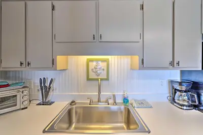 a kitchen with a sink and white cabinets at Steps to the Beach PCB Condo with Balcony! in Panama City Beach