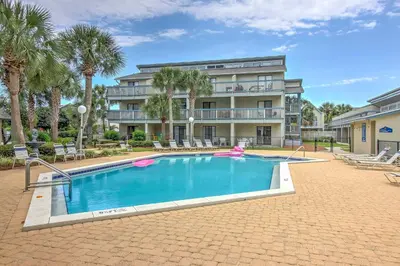 a swimming pool in front of a building with palm trees at Steps to the Beach PCB Condo with Balcony! in Panama City Beach