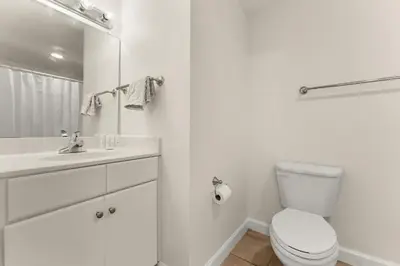 a white bathroom with a toilet and a sink at Shores of Panama Beachfront 2nd Floor Unit 208! No elevators needed! in Panama City Beach