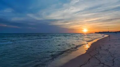 a beach with the sun setting over the water at Beachwood Villas 1C in Santa Rosa Beach