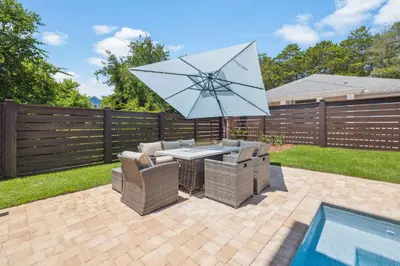 a patio with a table and umbrella next to a pool at White Sand Retreat by 30A Escapes in Seagrove Beach