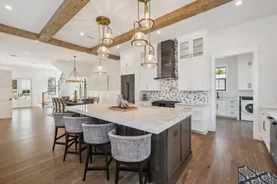 a kitchen with white cabinets and a large island with bar chairs at White Sand Retreat by 30A Escapes in Seagrove Beach