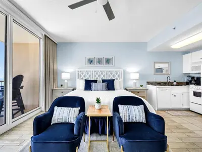 a bedroom with a bed and two blue chairs at New BeachFront-Majestic Beach Resort-Starbucks in Panama City Beach