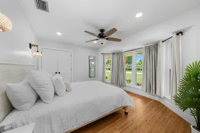 a white bedroom with a bed and a ceiling fan at Salt Water POOL, GAME room, KING BED &PET friendly in Panama City