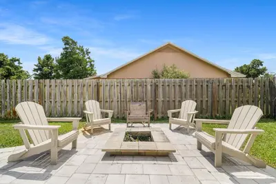 a patio with four chairs and a wooden fence at Salt Water POOL, GAME room, KING BED &PET friendly in Panama City