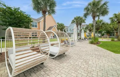 two wooden benches sitting on a sidewalk in front of a house at 3 Bedroom Luxury Condo with Resort Pool, Game Room, and Gym in Panama City Beach