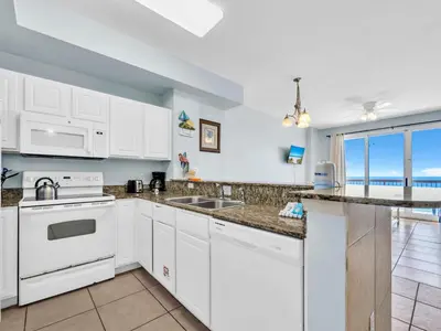 a kitchen with white appliances and a view of the ocean at Sunrise Beach #1707 in Panama City Beach