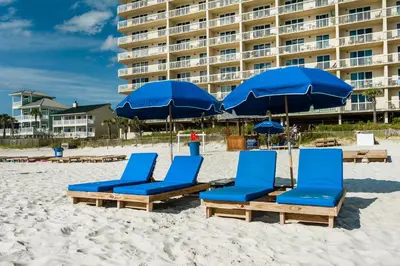 a group of blue chairs and umbrellas on a beach at Celadon 203 in Panama City Beach