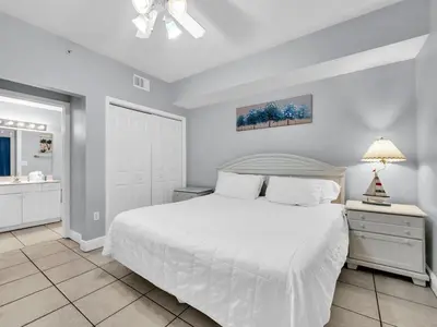 a white bedroom with a white bed and a window at Celadon 203 in Panama City Beach