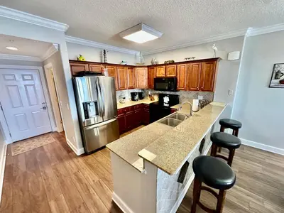 a kitchen with a stainless steel refrigerator and wooden cabinets at Tropic Winds 2108 in Panama City Beach