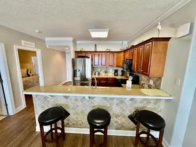 a kitchen with a counter and stools at Tropic Winds 2108 in Panama City Beach