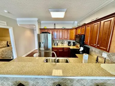 a kitchen with wooden cabinets and a stainless steel refrigerator at Tropic Winds 2108 in Panama City Beach