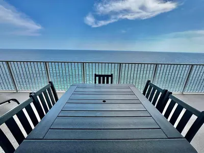 a wooden table with two chairs and the ocean at Tropic Winds 2108 in Panama City Beach