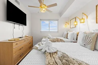 a bedroom with two beds and a flat screen tv at Sterling Breeze Unit 2106 in Panama City Beach
