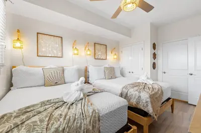 two beds in a bedroom with white walls at Sterling Breeze Unit 2106 in Panama City Beach