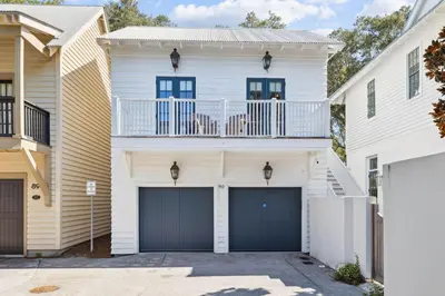 a white house with a balcony and garage at 90 N Cartagena Carriage House by 30A Escapes in Rosemary Beach