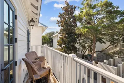a porch with a chair and a fence and trees at 90 N Cartagena Carriage House by 30A Escapes in Rosemary Beach
