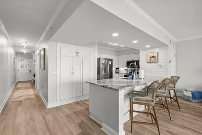 a kitchen with white walls and a counter with chairs at Emerald Beach Resort 1734 - Amazing Views, Beachfront, King Bed, 3 Pools, Starbucks in Panama City Beach