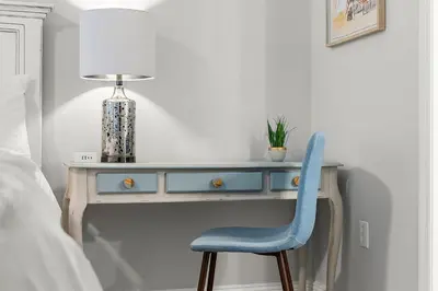 a desk with a blue chair next to a bed at Emerald Beach Resort 1734 - Amazing Views, Beachfront, King Bed, 3 Pools, Starbucks in Panama City Beach