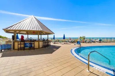 a swimming pool with a bar next to the ocean at Emerald Beach Resort 1734 - Amazing Views, Beachfront, King Bed, 3 Pools, Starbucks in Panama City Beach