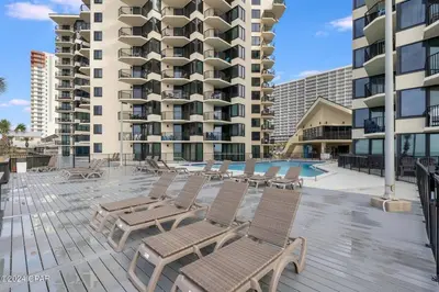 a deck with chairs and a pool in front of a building at Sunbird Resort - 11th Floor - Free Beach Chairs - by Sunbird Rentals in Panama City Beach