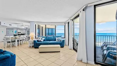 a living room with a blue couch and a view of the ocean at Sunbird Resort - 11th Floor - Free Beach Chairs - by Sunbird Rentals in Panama City Beach