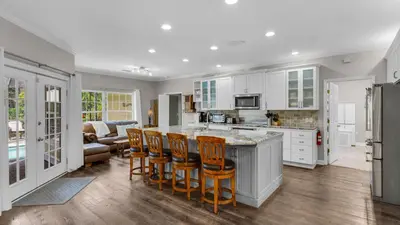 a kitchen with white cabinets and a island with bar stools at Secluded Sanctuary By the Sea in Seacrest