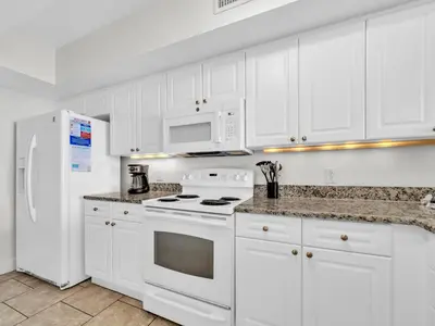 a kitchen with white cabinets and a stove and a refrigerator at Emerald Beach 2336 by Emerald Coast Retreats in Panama City Beach