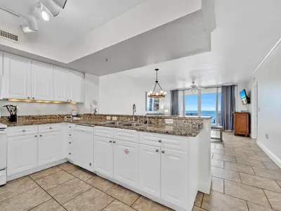 a kitchen with white cabinets and a view of the ocean at Emerald Beach 2336 by Emerald Coast Retreats in Panama City Beach