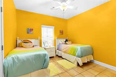 two beds in a room with yellow walls at Little Narnia - Colorful Beach House Private Pool in Seacrest