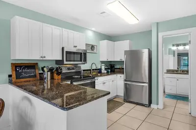 a kitchen with white cabinets and a stainless steel refrigerator at Sunny Daze at Beachwood Villas - Walk to Beach Outdoor Pools & More in Santa Rosa Beach