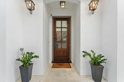 a hallway with a wooden door and two potted plants at Rosemary Bluegrass in Rosemary Beach