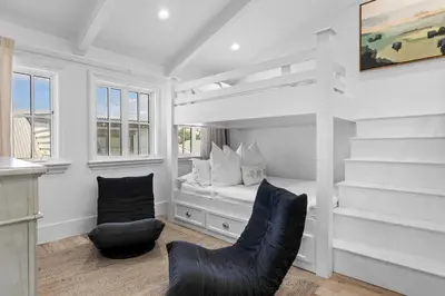a white room with a bed and a chair at Rosemary Bluegrass in Rosemary Beach