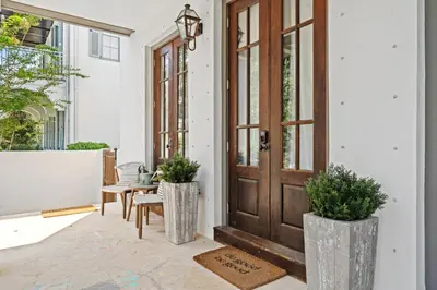 a porch with a wooden door and two plants at Rosemary Bluegrass in Rosemary Beach