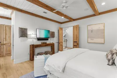 a bedroom with a white bed and a flat screen tv at Rosemary Bluegrass in Rosemary Beach
