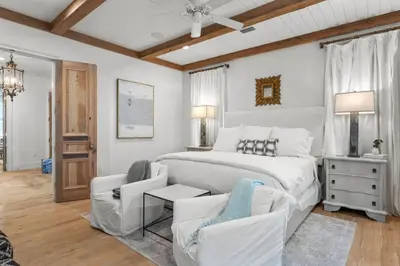 a white bedroom with a bed and two chairs at Rosemary Bluegrass in Rosemary Beach