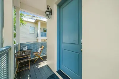 a blue door on a balcony with a table and chairs at Piccadilly Carriage House in Rosemary Beach