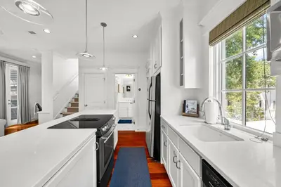 a kitchen with white counters and a large window at Piccadilly Carriage House in Rosemary Beach
