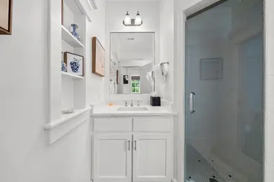 a white bathroom with a sink and a shower at Piccadilly Carriage House in Rosemary Beach