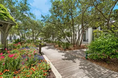 a wooden pathway through a garden with flowers at Piccadilly Carriage House in Rosemary Beach